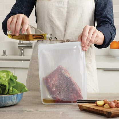 Mujer en cocina preparando carne para cocinar en bolsa de silicona platino grande rectangular transparente de Stasher - LLevar & LLevar