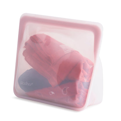 Bolsa de silicona platino mediana con base rosa con prendas de ropa en su interior de Stasher - LLevar & LLevar