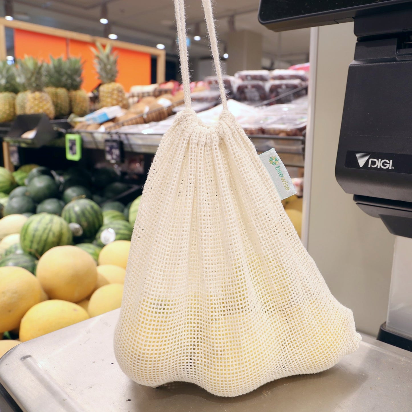 Bolsa de rejilla con limones sobre báscula de supermercado - LLevar & LLevar