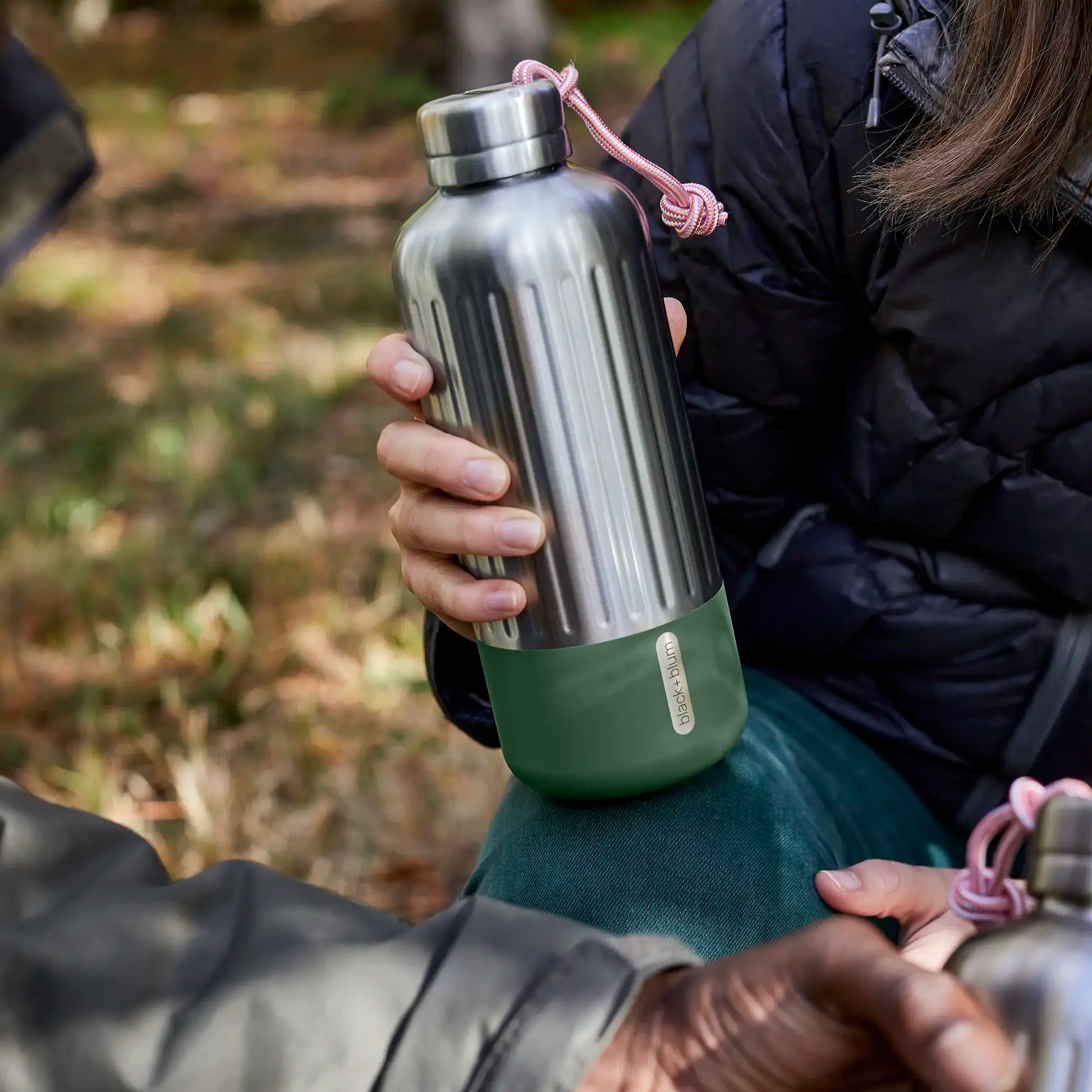 Botella Isotérmica Black+Blum 850ml Explorer cogida con una mano en el campo